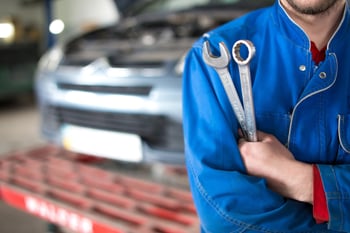 Auto shop technician holding tools in a service garage ready to address customer dispute