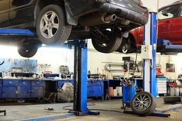 Two vehicles up on lifts in an auto shop after a comeback