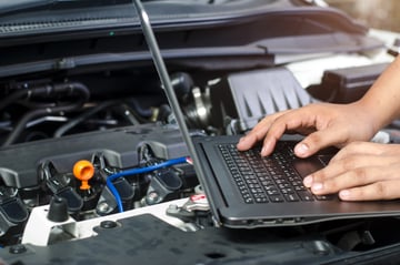 Auto shop tech diagnosing issues under the hood of a vehicle after a comeback