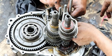 Technician rebuilding a disassembled transmission unit on a workbench